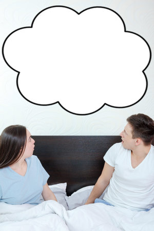 Handsome man and pretty surprised woman in bedroom looking up at thinking speech bubble, comic cloud...