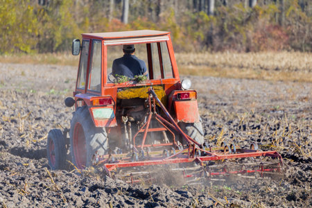 Farmer in Tractor Preparing Land for Sowing,  Agriculture and Working. Red Tractor Plowing in...