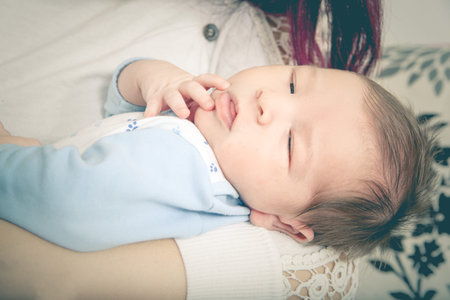 One Month Old Baby Boy in Comfort of Moms Arms. Fall Asleep in Mother's Arms.