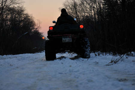 An ATV on wheels ride on a taiga forest road in winter eveningの写真素材