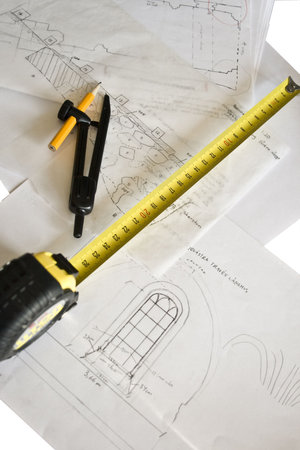 Measuring tape and compasses lying on drawings of building interiors