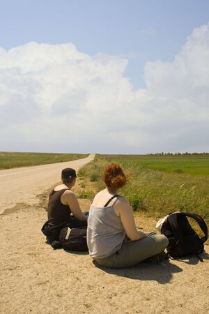  two girls waiting for the bus by a deserted roadの写真素材