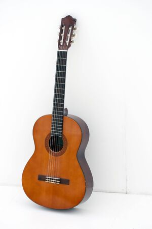 acoustic guitar leaning on a white wallの写真素材