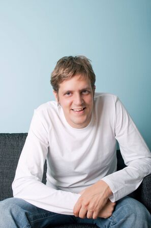 casual young man smiling and relaxing on the sofaの写真素材