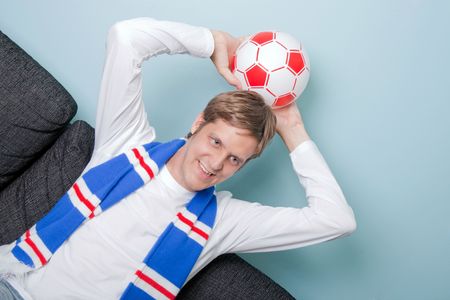 smiling young man supporting his football teamの写真素材