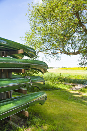 Image of green canoes on a rack by the river.の写真素材