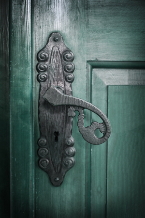 Image of a cast iron door handle on a green door.の写真素材