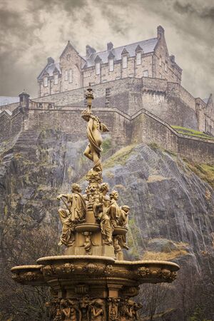 Image of a gold fountain in Princess Street gardens, Edinburgh. Above is Edinburgh castle.のeditorial素材