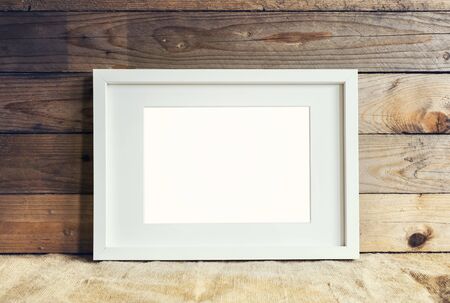 Image of white standing mockup frame on wooden background with burlap.の写真素材
