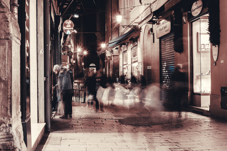 BOLOGNA, ITALY - FEBRUARI 08, 2017. Pedetrians on the street and lit up shop windows.の写真素材