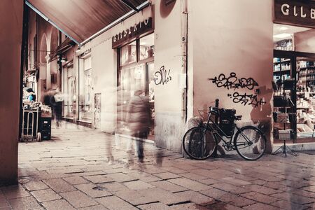 BOLOGNA, ITALY - FEBRUARI 08, 2017. Pedetrians on the street and lit up shop windows.のeditorial素材