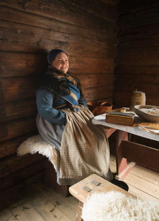 OSLO, NORWAY - December 01, 2019: Woman dressed in traditional historic clothing sitting by table in the Cultural History Museum.のeditorial素材