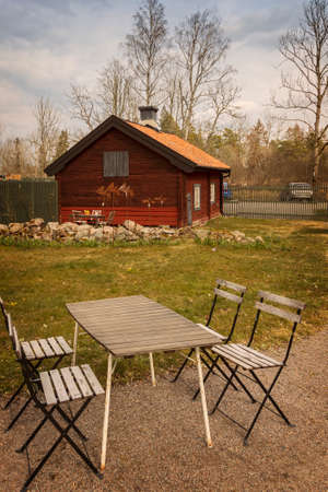 Small cottage in rural setting, with cafe table and chairs.のeditorial素材