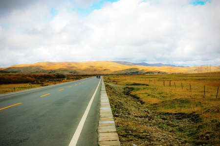 The autumn grassland with a roadの写真素材