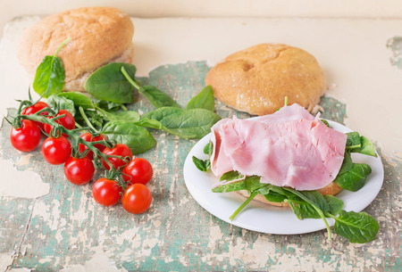 Homemade sandwich with ham, spinach and whole grain buns over the rustic wooden tableの写真素材
