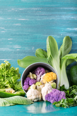 Organic rainbow cauliflower with various greens: bok choi, lettuce, bell pepper, basil and parsley on black background. Top viewの写真素材