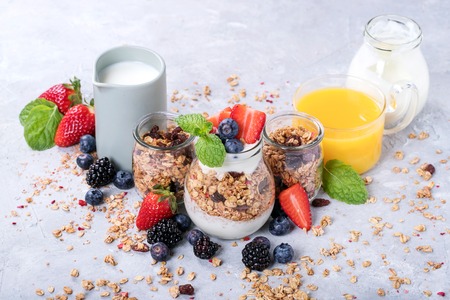 Homemade granola breakfast served with berries, orange juice, yoghurt and decorated with mint leaves. Rustic breakfast Conceptの写真素材