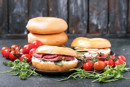 Home made ham and chicken bagels served with fresh organic spinach, ruccola, cottage cheese and tomatoes. Breakfast concept.の写真素材