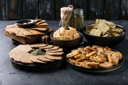 Assortment of snacks: garlic and coriander crackers, chips and biscuits served with oregano and corianderの写真素材