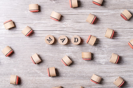 Word mad made from wooden letters over gray wooden background. Top view, flat lay. Copy space