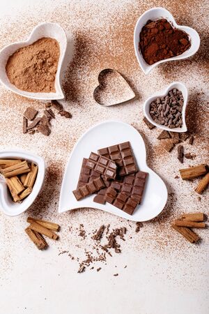 Saint valentine's day ceramic plates in shape of a heart with chocolate, cinnamon and cacao over white texture background. Top view, flat lay. Copy spaceの写真素材