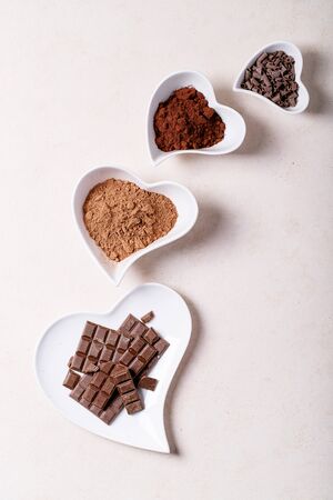 Saint valentine's day ceramic plates in shape of a heart with chocolate and cacao over white texture background. Top view, flat lay. Copy spaceの写真素材