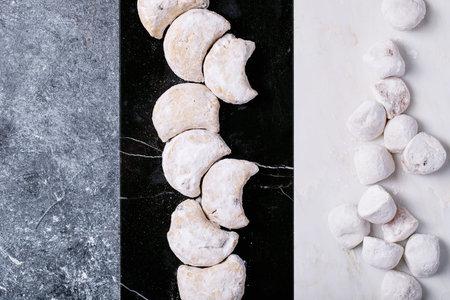 Variety of traditional Greek sweets cookies kourabiedes and akanes lukum in sugar powder over blue texture background. Top view, flat layの写真素材