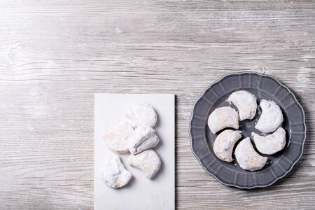 Variety of traditional Greek sweets cookies kourabiedes and akanes lukum in sugar powder over gray wooden texture background. Top view, flat layの写真素材