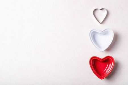 Saint valentine's day ceramic plates in shape of a heart over brown texture background. Top view,...
