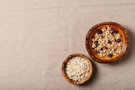 Granola breakfast in wooden bowl served with fresh greek yogurt, strawberry jam and dry oats over a cloth brown background. Top Viewの写真素材