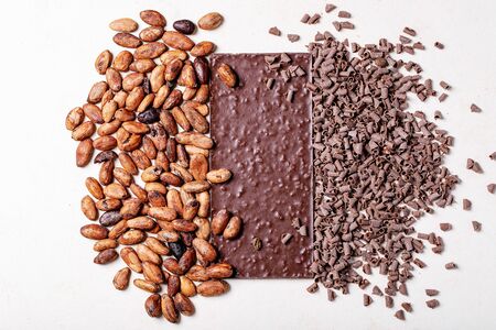 Dark chocolate served with cacao beans over white texture background. Top view, flat lay. Copy spaceの写真素材