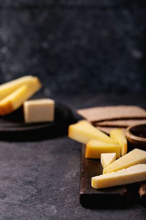 variation of hard and semi-hard cheese served with sweet jam over dark textured backgroundの写真素材