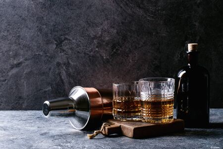 Glass of Irish whiskey with glass bottle and copper shaker over dark texture background. Copy spaceの写真素材