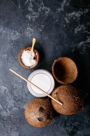 Coconut oil and milk in glass cup over dark texture background. Top view, flat lay. Copy spaceの写真素材