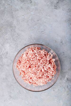 Raw minced meat in glass bowl over white texture backdround. Top view, flat lay. Copy spaceの写真素材