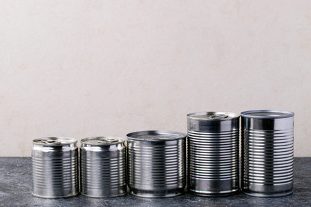 Canned food in metal cans over white texture background. Copy space. Food supply concept
