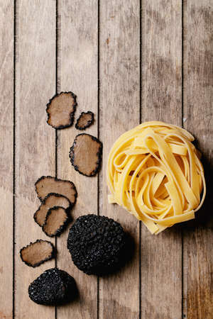 Home made egg pasta served with truffles, truffle infused oil and saltover wooden background. New concept of raw foods. Top view, flat lay. Copy spaceの写真素材