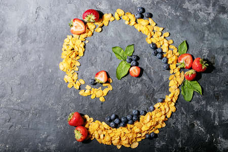 Golden cerials served with strawberry, blueberry and mint over dark texture background. Top view, flat lay. Copy spaceの写真素材