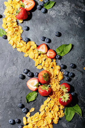 Golden cerials served with strawberry, blueberry and mint over dark texture background. Top view, flat lay. Copy spaceの写真素材