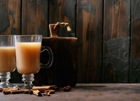 Masala chai served with cinnamon sticks and anise over dark wooden backgroundの写真素材