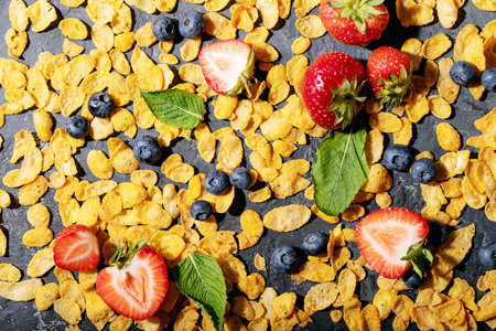Golden cerials served with strawberry, blueberry and mint over dark texture background. Top view,...