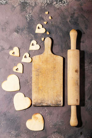 Handmade cookies in shape of heart over brown texture background. Top view, flat layの写真素材