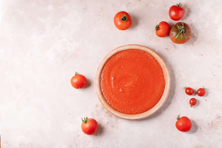Homemade tomato soup served with fresh bio tomatoes over white texture backgroundの写真素材
