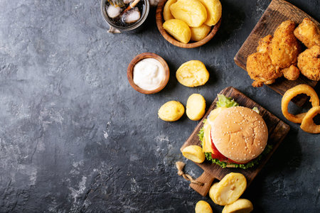 Home made burgers with onion rings and fried potatoes served with cola and crispy fried breaded...