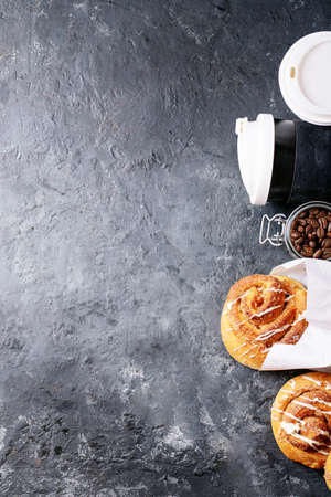 Baked cinnamon buns served with cinnamon and coffee over white texture background. Top view, flat lay. Copy space. Take away conceptの写真素材