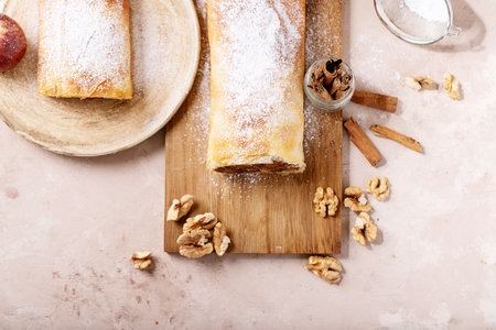 Apple strudel served with fresh apples, cinnamon sticks and walnuts over white texture backgroundの写真素材