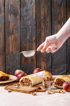 Apple strudel served with fresh apples, cinnamon sticks and walnuts over white texture backgroundの写真素材
