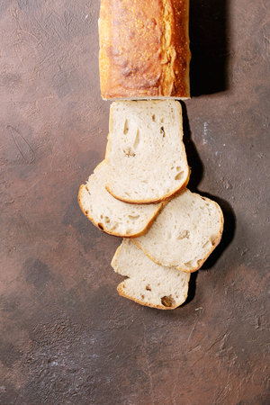 Homemade sliced white bread over brown texture background. Top view, flat lay. Copy space