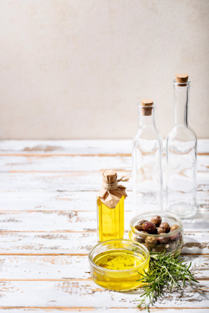Olive oil in glass bowl served with fresh olives over white wooden backgroundの写真素材