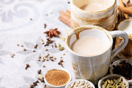 Masala chai served with cinnamon sticks, green cardamom seeds and anise over grey texture backgroundの写真素材